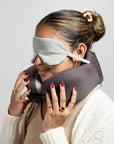 Woman wearing the travel pillow around her neck with the eye mask over her eyes