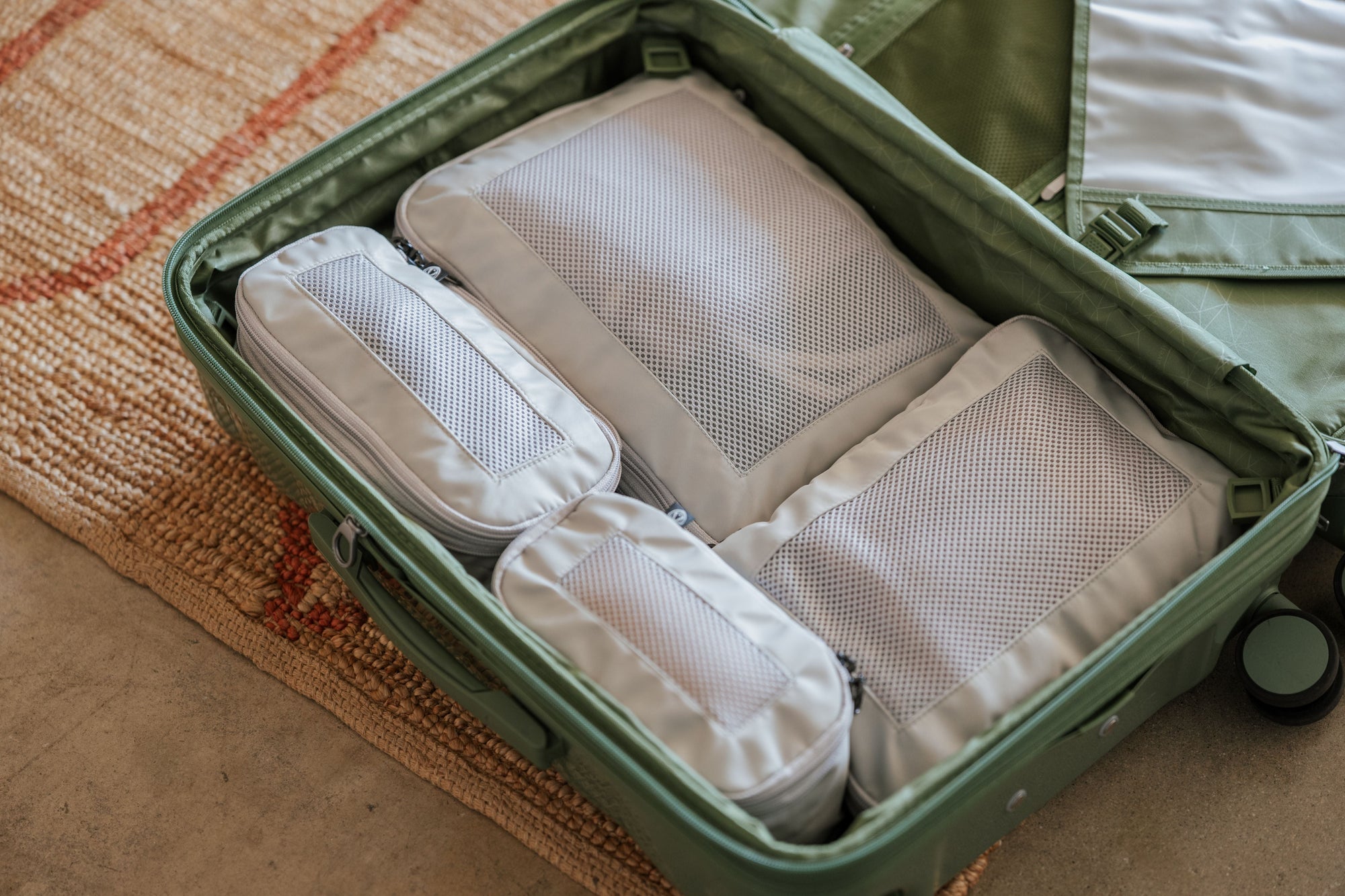 four traveler choice compression packing cubes inside a green suitcase
