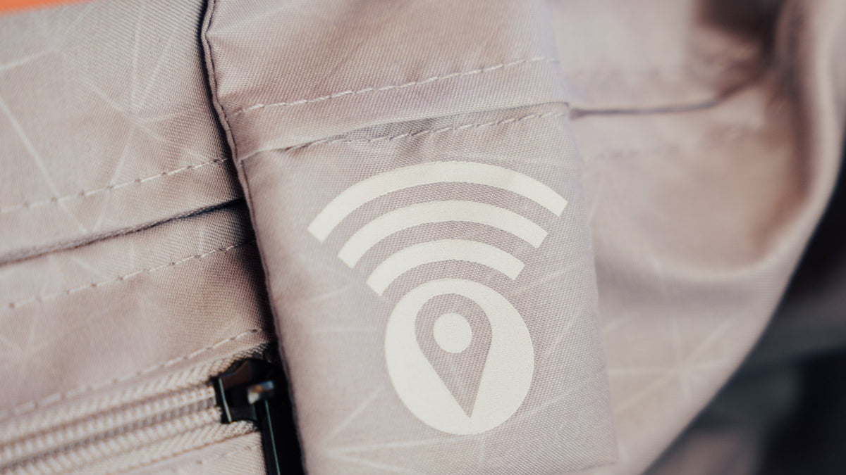 Light gray suitcase lining with a sleeve pocket printed with a location tracker icon.