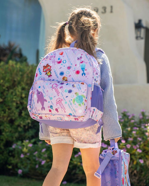 A girl walks to school wearing the Ocean backpack and carrying the matching lunch bag.