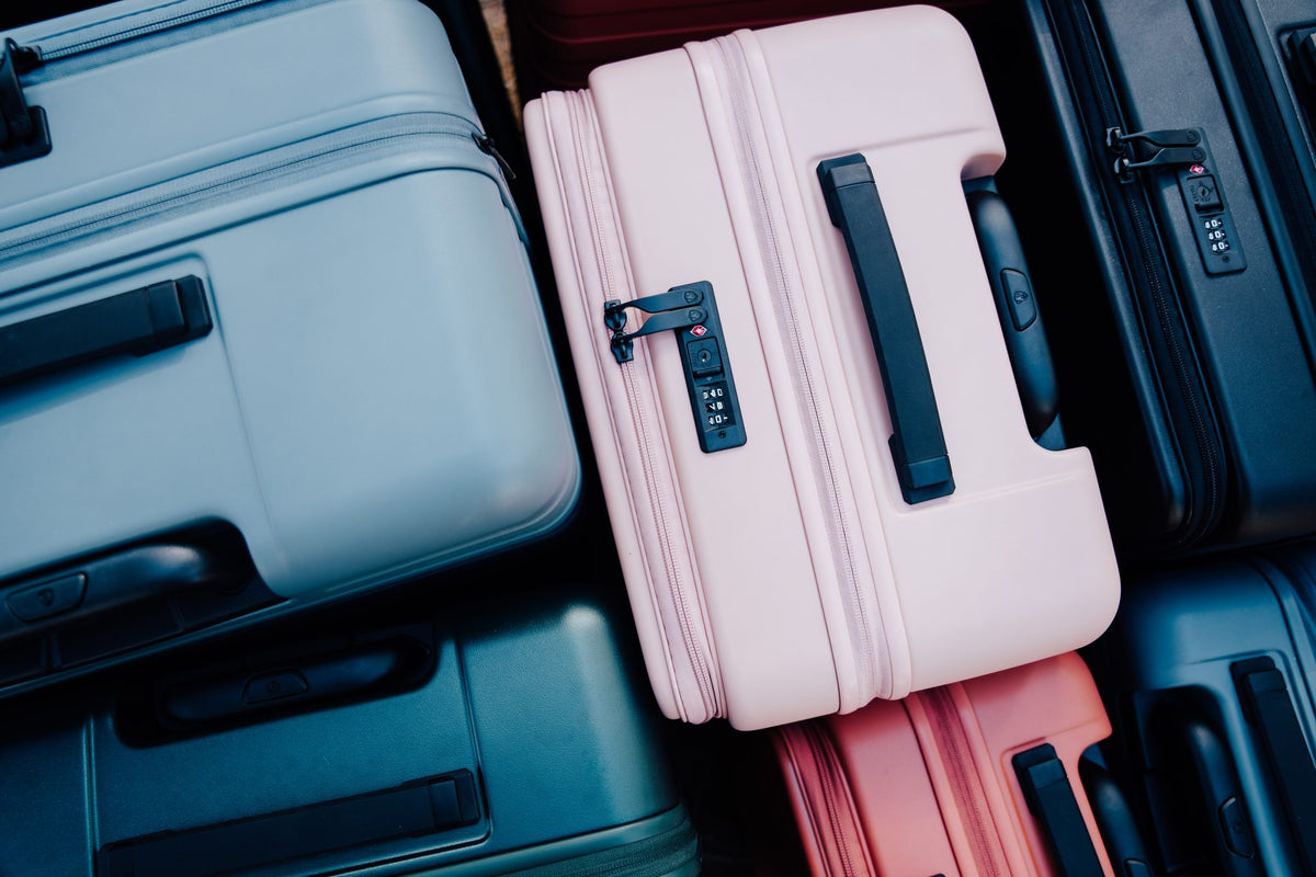Overhead view of Novia hardside luggage in slate blue, pink, black and green