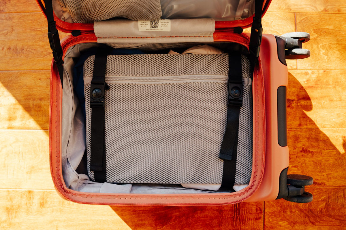 Open top compartment of an orange Novia carry-on with a packing cube inside