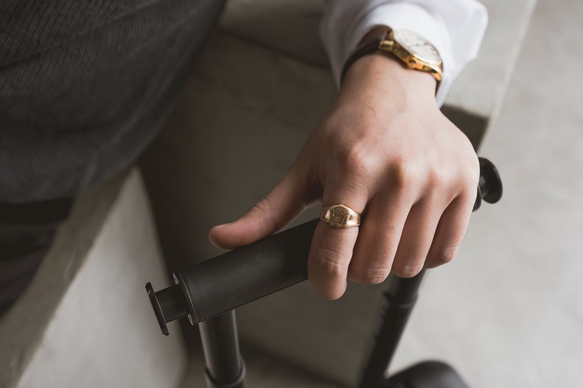 A hand gripping the extended telescoping handle of a suitcase against a warm plaster wall