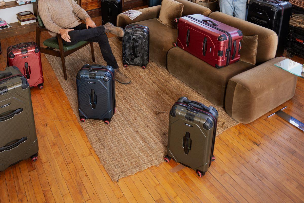 Rugged trunk-style cases in olive, red, charcoal and camouflage arranged across a loft living room floor